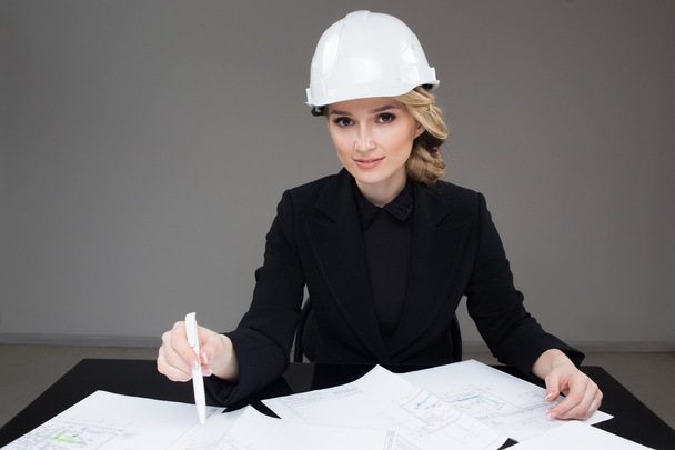 Woman architect with drawings. Beautiful girl in a building helmet - Fotó, kép