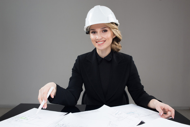 Woman architect with drawings. Beautiful girl in a building helmet - Foto, Imagen
