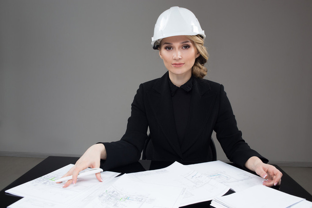 Woman architect with drawings. Beautiful girl in a building helmet - Valokuva, kuva