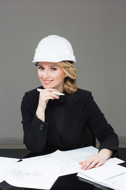 Woman architect with drawings. Beautiful girl in a building helmet - Fotografie, Obrázek