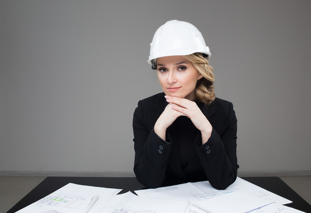 Woman architect with drawings. Beautiful girl in a building helmet - Фото, изображение