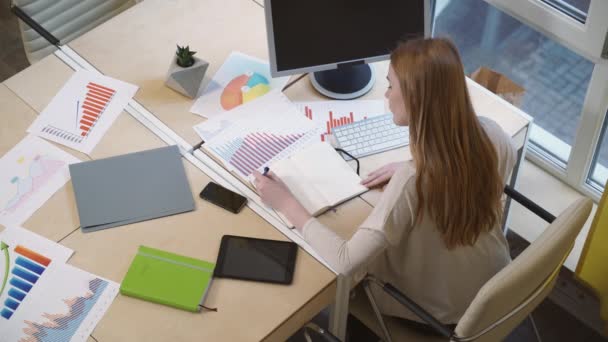 慎重にチャートの勉強ノートを作る職場では、座っている女性. - 映像、動画