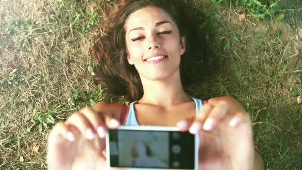 Tři mladí dospělí s selfie, ležící na trávě - Záběry, video