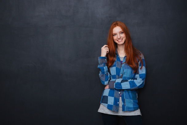 Happy woman with red hair standing over blackboard background - Φωτογραφία, εικόνα