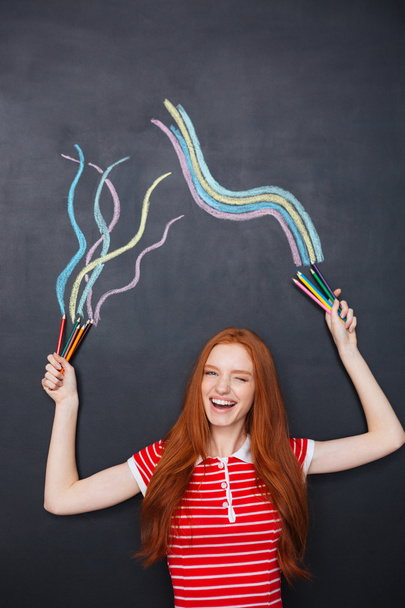 Charming woman laughing and drawing on blackboard background - Foto, immagini