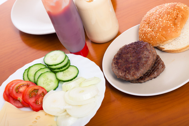Table with hamburgers and vegetable - Photo, Image