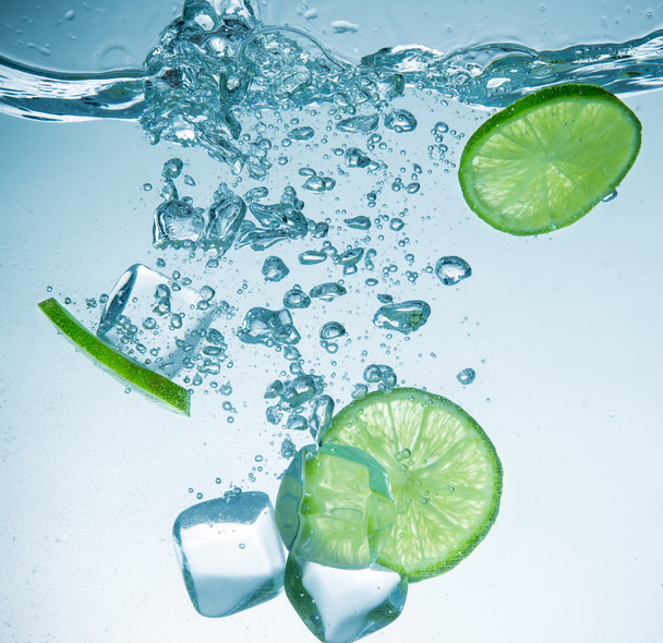 Limes with water splash and ice cubes - Zdjęcie, obraz