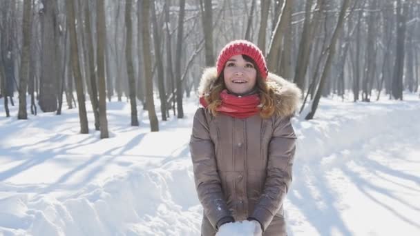 Feliz joven mujer lanza nieve en el parque, slow motion
 - Imágenes, Vídeo