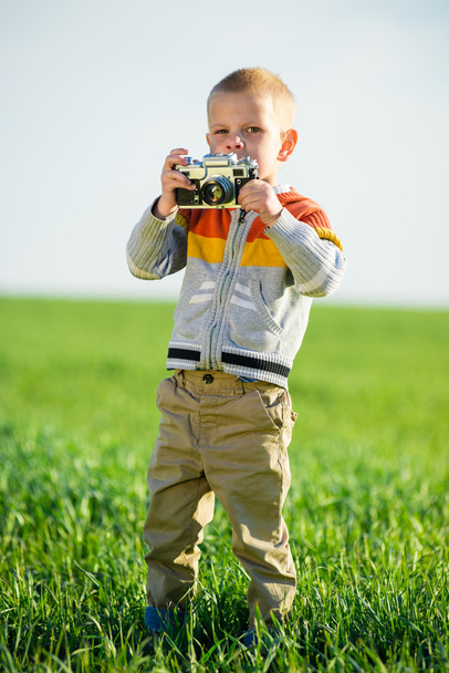 Little boy with an old camera shooting outdoor. - Фото, изображение