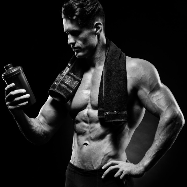 Μυϊκής εκγύμνασης αρσενικό bodybuilder εκμετάλλευση πρωτεΐνη ανακινείται μπουκάλι - Φωτογραφία, εικόνα