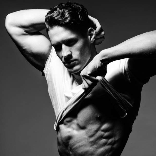 Knappe bodybuilder toont zijn grote lichaamsbouw, perfecte schouders - Foto, afbeelding