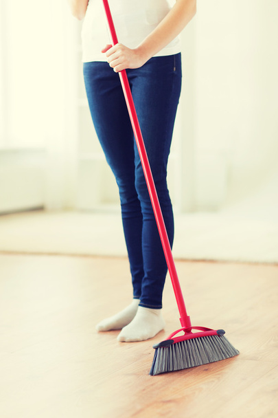 close up of woman legs with broom sweeping floor - Фото, изображение