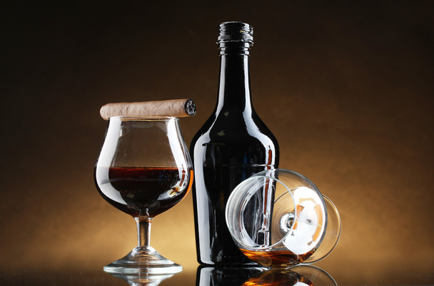 Bottle and glasss of brandy and cigar on brown background - Fotoğraf, Görsel