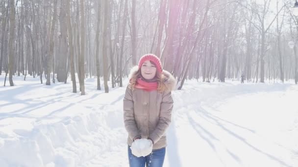 幸せな若い女が公園、スローモーションで雪をスローします。 - 映像、動画