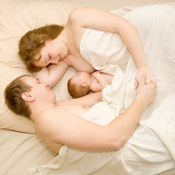 Beyaz bir yatakta yatmak güzel bir aile. - Fotoğraf, Görsel