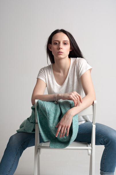 Young beautiful girl sitting on the wooden chair - Foto, afbeelding