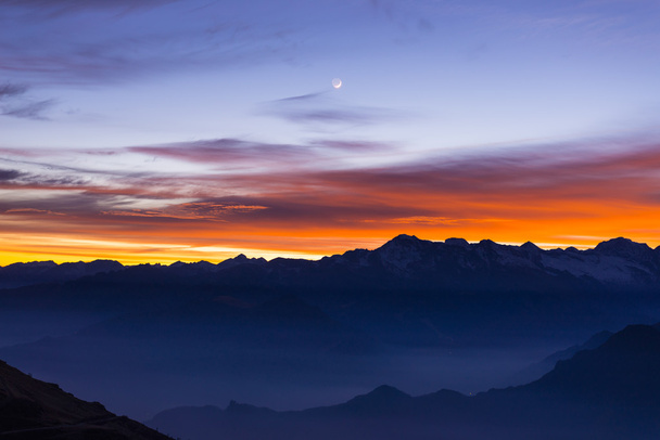 Mountain silhouette and stunning sky with moon at sunset - Photo, Image