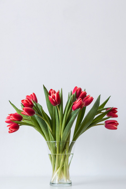 Барвисті червоні тюльпани у вазі на столі
 - Фото, зображення