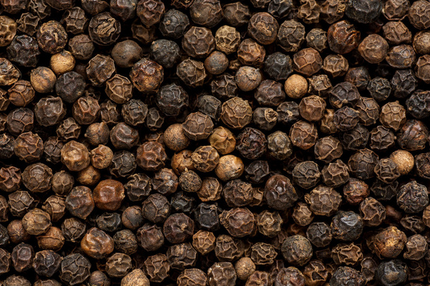 Black pepper grains as background close up - Photo, image