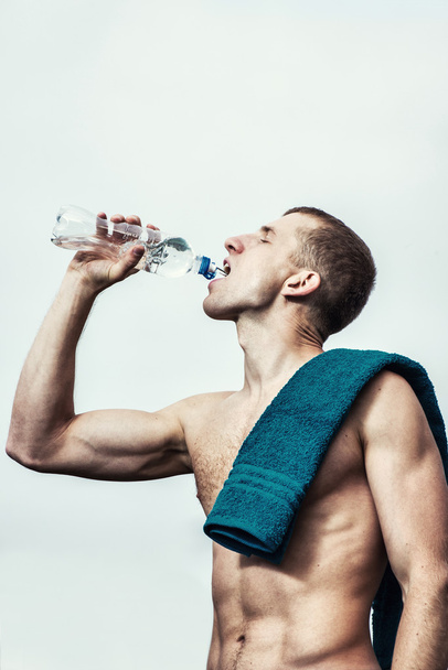 Muscular young man after a workout  drinking  bottle of water - Fotoğraf, Görsel