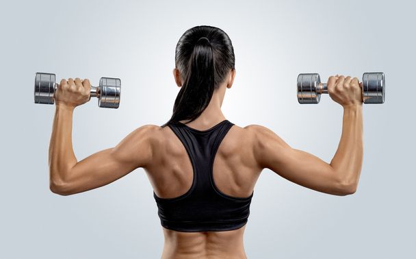 Fitness woman in training muscles of the back with dumbbells - Foto, Bild