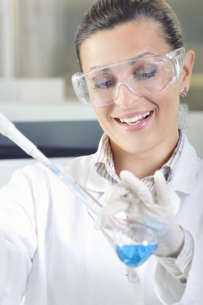 Jovem e atraente cientista estudante de doutorado observando a mudança de cor do indicador azul após a destilação da solução em laboratório químico
 - Foto, Imagem