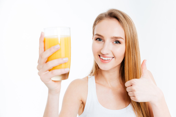 Woman holding glass with fresh kuice and showing thumb up - Foto, afbeelding