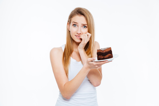 Doubtful woman on diet thinking and holding piece of cake - Zdjęcie, obraz
