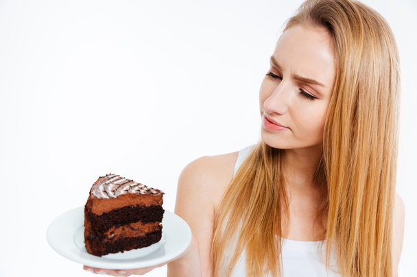 Pensive beautiful woman looking at piece of chocolate cake  - Fotó, kép