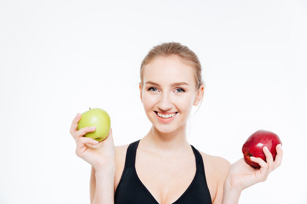 Happy beautiful sportswoman holding green and red apples  - Photo, image