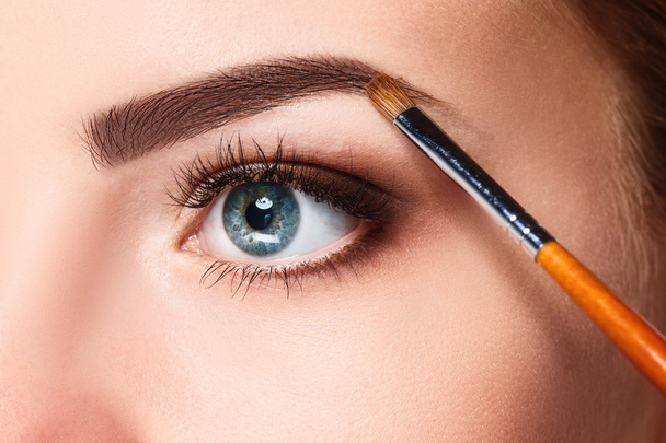Beautiful female eyes with bright blue make-up and brush - Фото, изображение