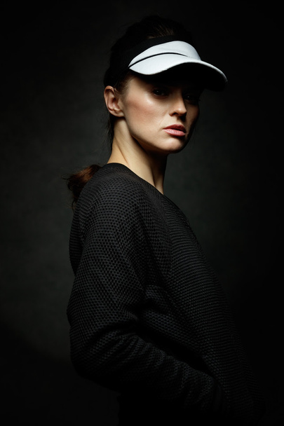 Portrait of young fit woman against black background - Foto, imagen