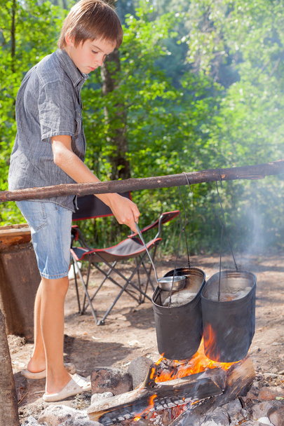 Boy cooking on campfire - Foto, afbeelding
