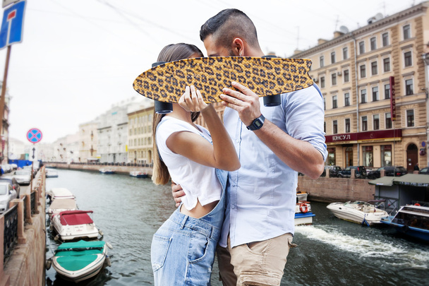 young couple kissing hiding behind a skateboard - Photo, Image