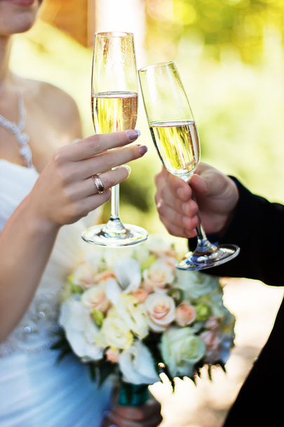 Νύφη και γαμπρός τσούγκριζαν ποτήρια την ημέρα του γάμου. - Φωτογραφία, εικόνα