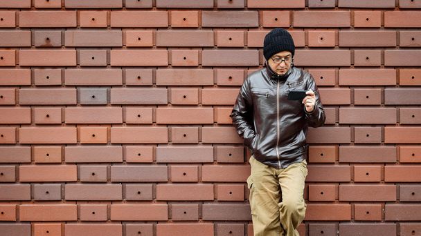 Un homme asiatique dans une veste brune avec son smartphone
 - Photo, image