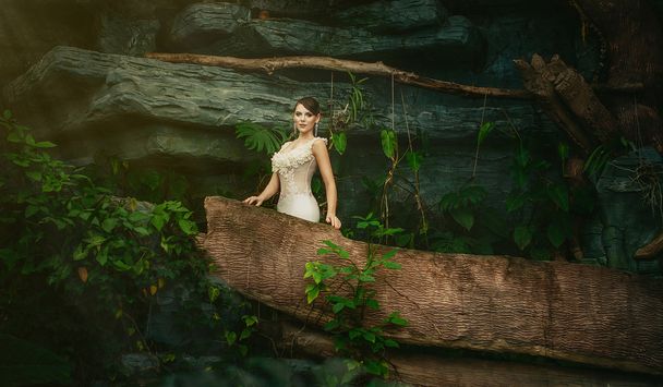 beautiful young brunette woman in a long white dress, blue eyes, in the jungle. Bride in the jungle. - Fotó, kép