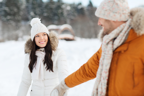 happy couple walking along snowy winter field - Zdjęcie, obraz
