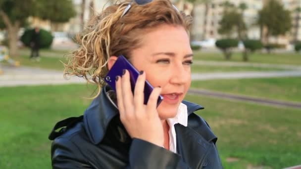 Business woman talking on mobile phone in a city park - Video