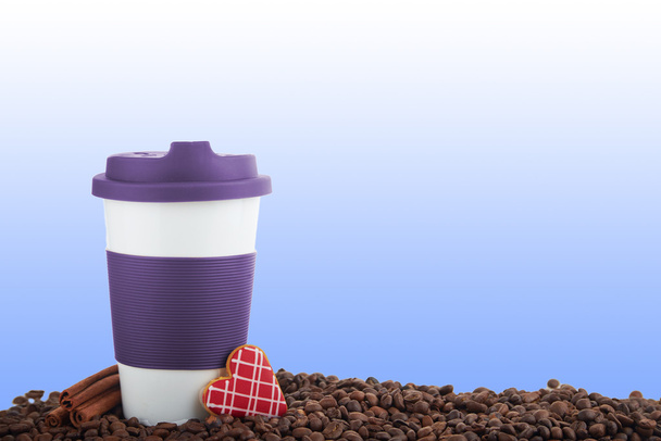 Керамическая чашка на вынос и кофейные зерна на синем фоне
 - Фото, изображение