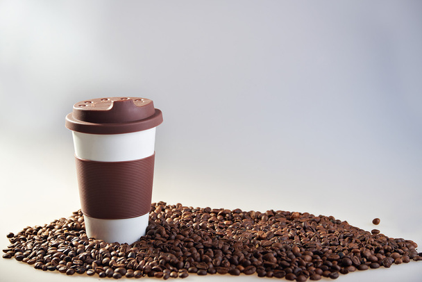 Takeaway ceramic cup and coffee beans on blue background - 写真・画像