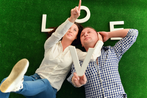 Feliz joven pareja acostada sobre una alfombra verde
  - Foto, Imagen