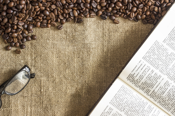 Fundo de grãos de café torrados espalhados na tela de serapilheira, copos e livro aberto
 - Foto, Imagem