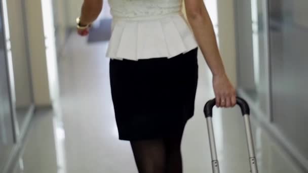Achterzijde van blonde vrouw in zwarte schoenen op hakken Runway lopen met koffer. - Video