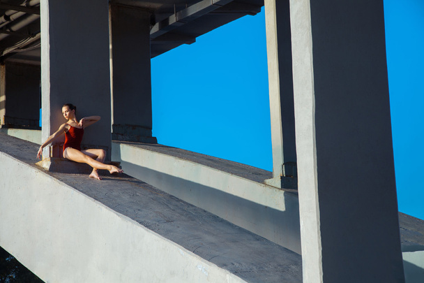 Young beautiful woman gymnast posing on bridge girder - Φωτογραφία, εικόνα