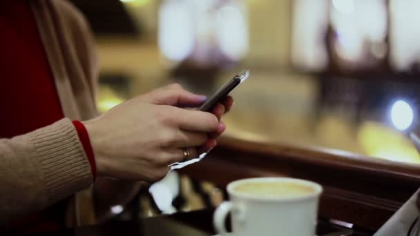 女性の手のテキスト メッセージ、カフェでスマート フォンを使用して. - 映像、動画