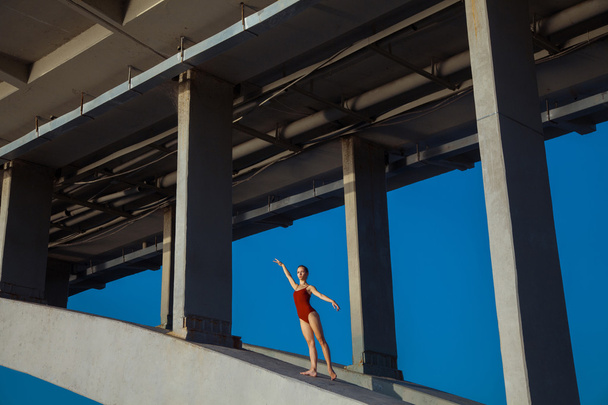 Young beautiful woman gymnast posing on bridge girder - Fotó, kép