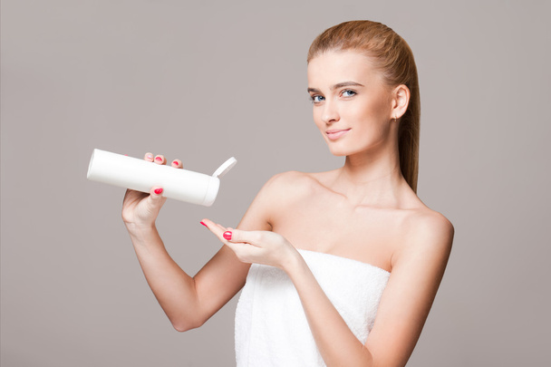 Blond woman using moisturizer. - Фото, зображення
