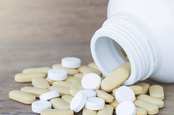Muitos comprimidos e vitaminas em garrafas de medicina em fundo de madeira
 - Foto, Imagem