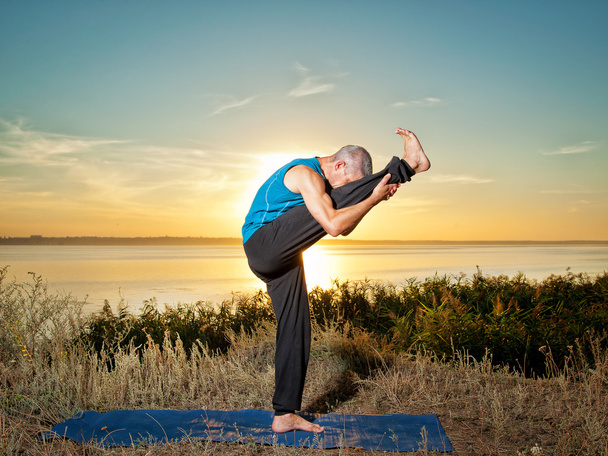 hombre sonriente haciendo ejercicios de yoga al aire libre
 - Foto, imagen